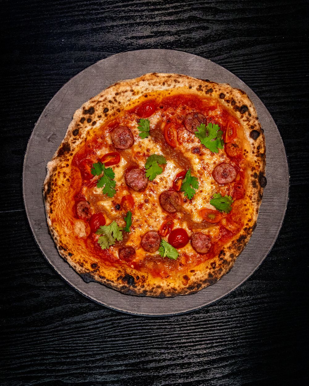 Pizza de chorizo y tomate de masa madre sobre piedra, vista desde arriba