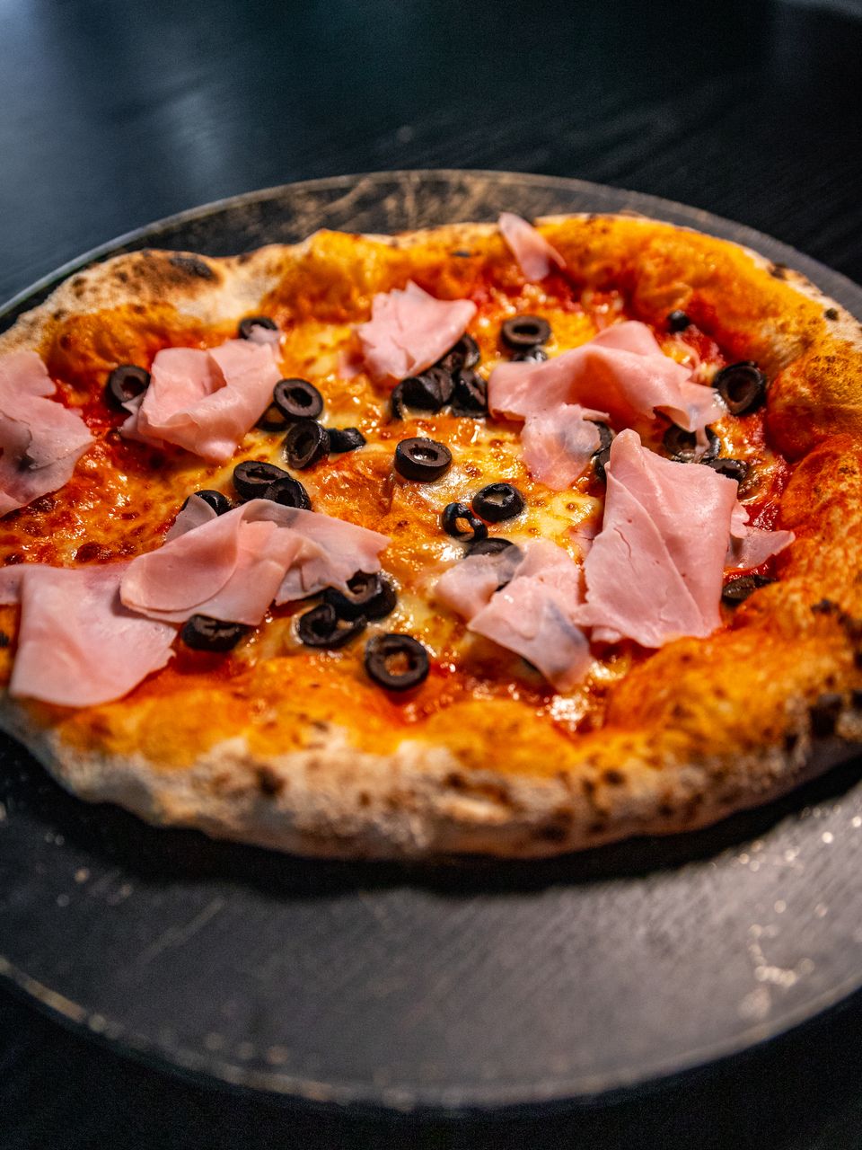Pizza de jamón y aceitunas negras de masa madre, recién salida del horno
