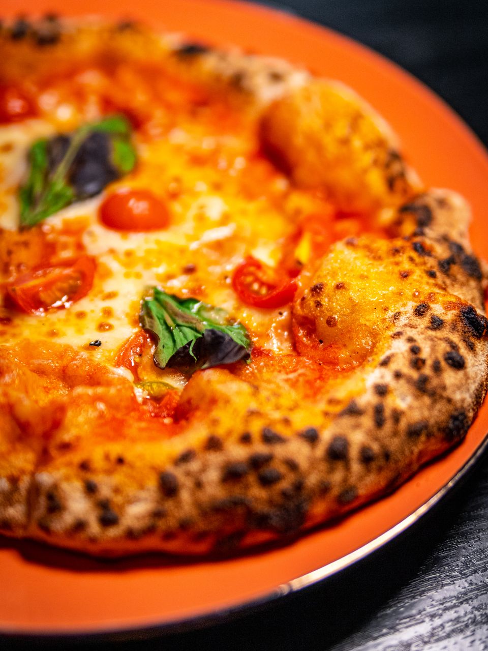 Pizza margherita de masa madre con tomate cherry, mozzarella y albahaca, corteza con ampollas quemadas